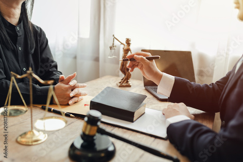 The lawyer sat in front of a laptop in a room filled with documents and smartphones, with a hammer and scales beside him, advising his female client on matters of justice and legal principles.