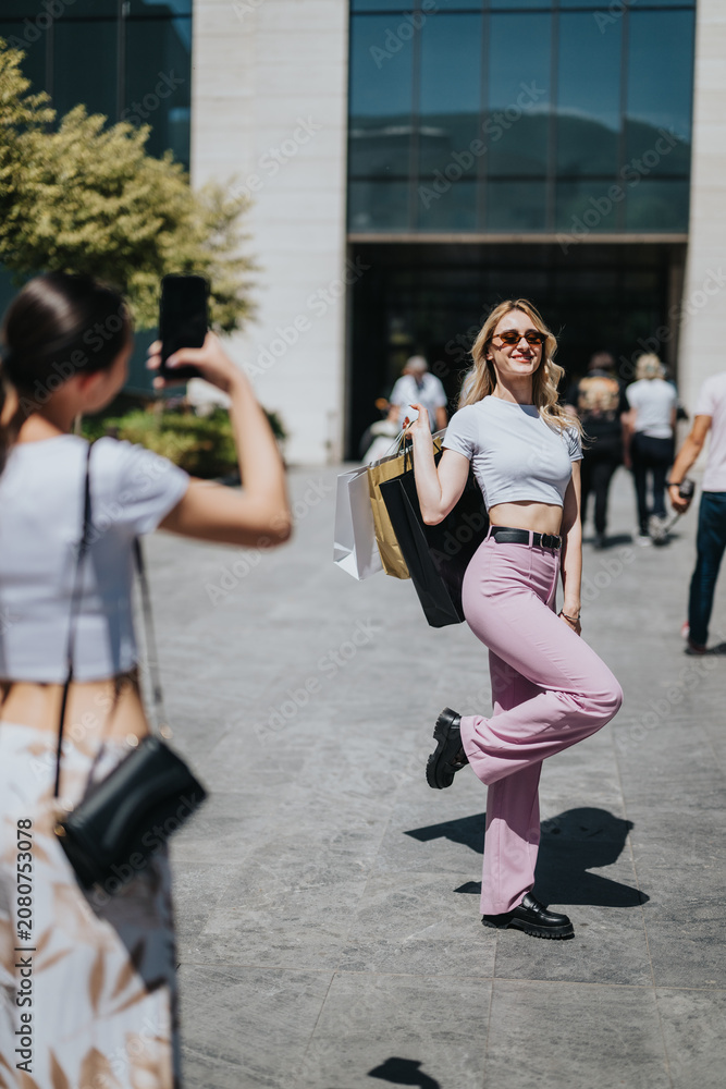 Fototapeta premium Two girls carry shopping bags as one poses and smiles for a photo. Friends enjoy a casual outdoor shopping moment in front of a contemporary storefront.
