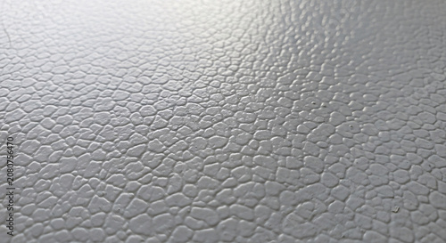 Close-up of a gray leather texture with a pebbled pattern and a shiny reflective surface