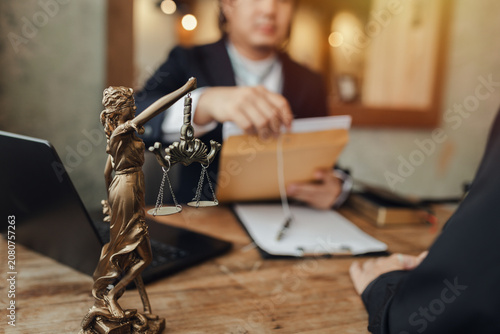 The lawyer sat in front of a laptop in a room filled with documents and smartphones, with a hammer and scales beside him, advising his female client on matters of justice and legal principles.