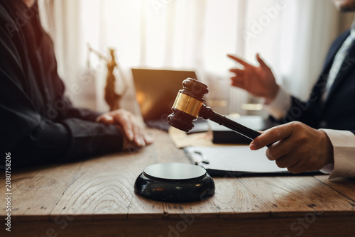 The lawyer sat in front of a laptop in a room filled with documents and smartphones, with a hammer and scales beside him, advising his female client on matters of justice and legal principles.
