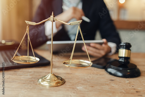 The lawyer sat in front of a laptop in a room filled with documents and smartphones, with a hammer and scales beside him, advising his female client on matters of justice and legal principles.