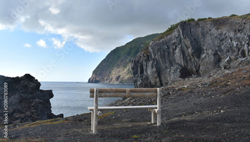 Canvastavla A wooden bench overlooking a dramatic volcanic coastline and vast ocean under a