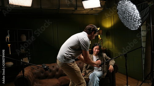 Foto Sound engineer adjusting lavalier microphone on talent during studio broadcast p