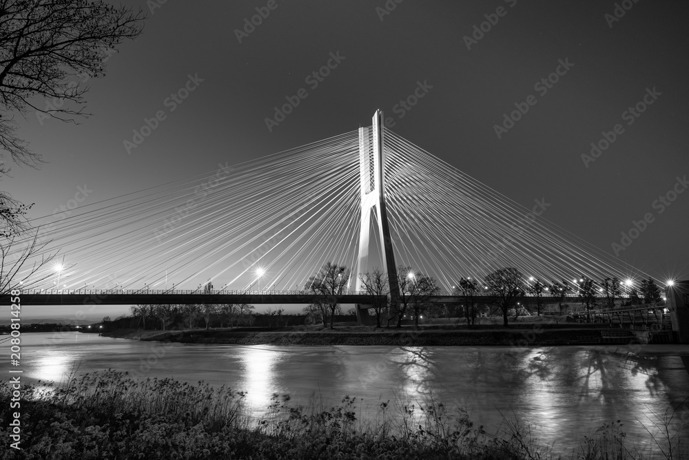 Fototapeta premium Black-and-white photo of a cable-stayed bridge illuminated in the evening.