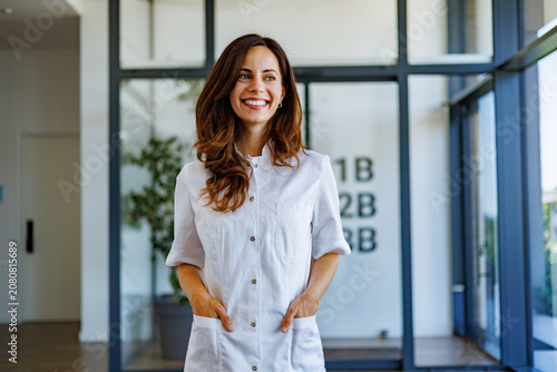Obraz na płótnie Smiling health professional wearing white uniform in modern clinic, representing