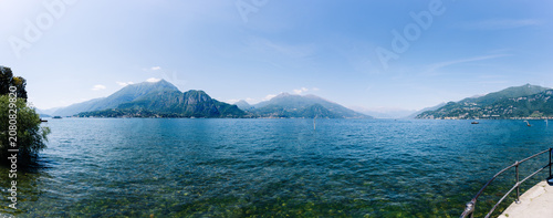 Panoramic view of Lake Como with surrounding mountains and clear blue sky, showcasing the natural beauty of Bellagio region in Italy