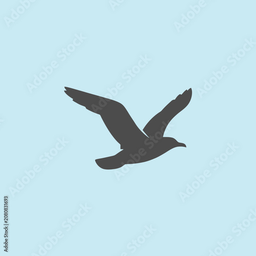 A dark silhouette of a bird flying against a light background
