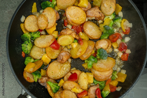 Canvastavla Cooking a mixture of potatoes and vegetables in a frying pan on a kitchen stove
