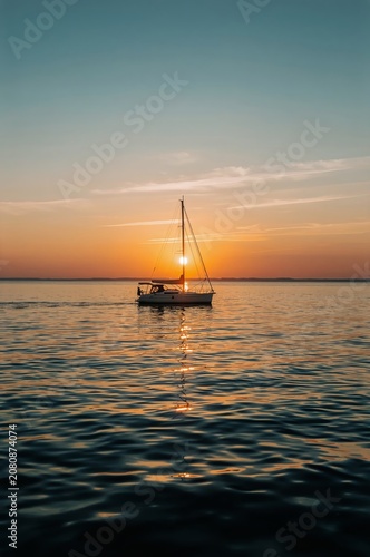 Sailboat on Still Water During Sunset With Orange and Blue Sky Above