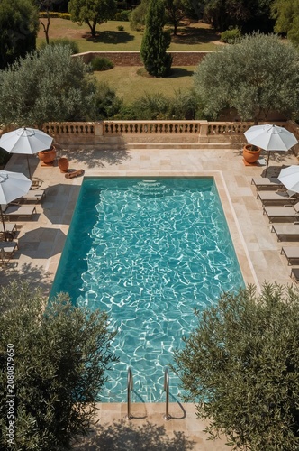 Swimming Pool With Lounge Chairs and Umbrellas in a Garden Setting on a Sunny...