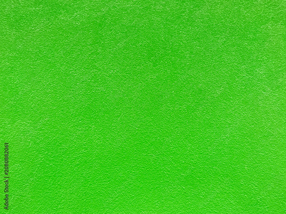 Fototapeta premium Full frame texture of a vibrant lime green painted wall. Rough stucco plaster surface background with a bright neon green color finish, modern abstract solid backdrop for graphic design.