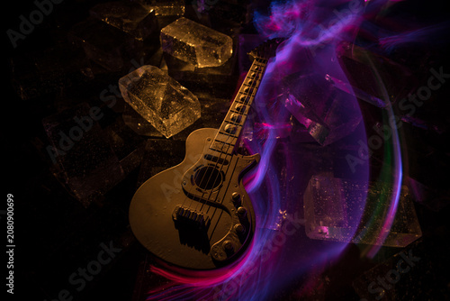 Music Concept: Guitar Miniature on a Dark Background with Vivid Light, Smoke, and Fire Effects. Golden electro guitar under a Dramatic Spotlight.