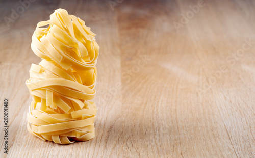 Foto Creative vertical tower of dry fettuccine nests standing on a natural wood surfa