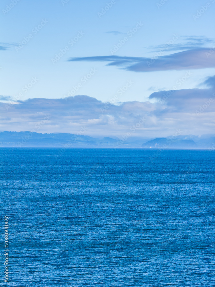 Obraz premium Calm Blue Ocean Horizon Over Sooke Coastline With Distant Islands and Cloudy Sky on Vancouver Island