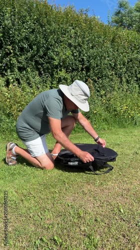 Mature man unpacking a portable metal fire pit bowl from its protective travel textile cover.