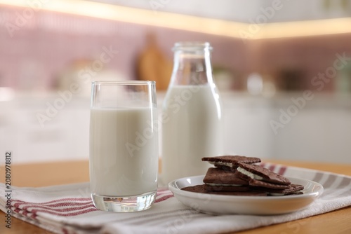 фотографія Fresh milk and chocolate sandwich cookies on wooden table in kitchen, closeup