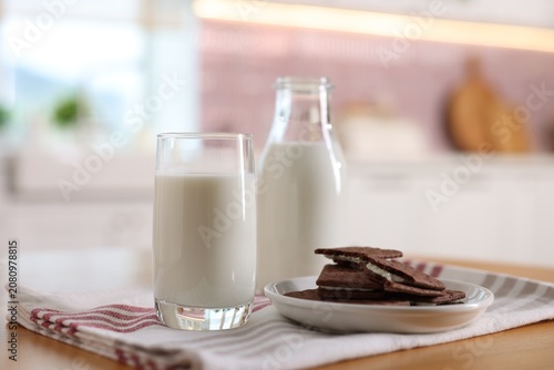 Foto Fresh milk and chocolate sandwich cookies on wooden table in kitchen, closeup