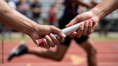 Athlete hands passing relay baton on a track