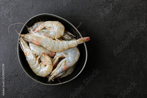 Raw shrimps in black bowl.