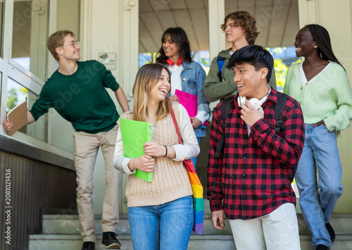 Multiethnic Group of Young Students Laughing While Exiting School Together