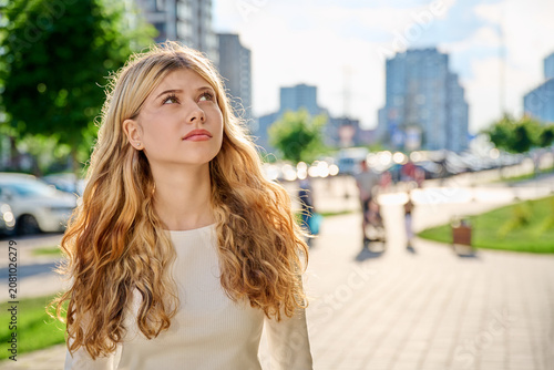 Dreamy teenage girl looking up on sunny city street