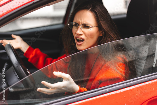 Canvas-taulu Frustrated young woman with long brunette hair in orange sweatshirt and eyeglass