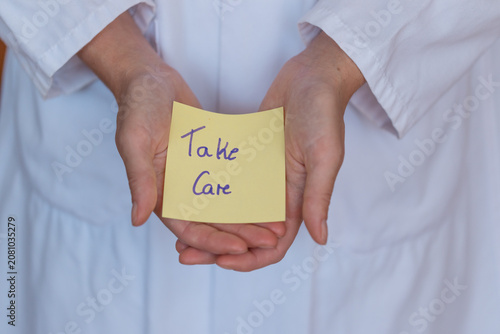 Принти на полотні Person in a white robe holds a yellow sticky note