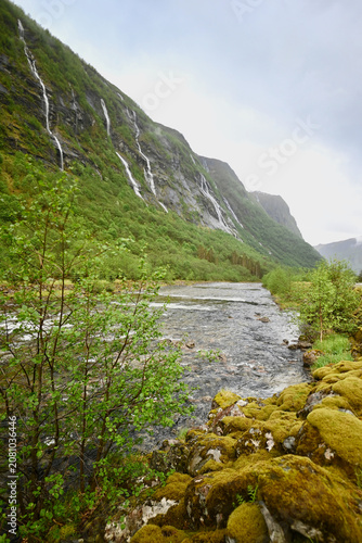 River valley near Dale, Norway, surrounded by steep cliffs with waterfalls cascading after rain during the lush days of late spring.