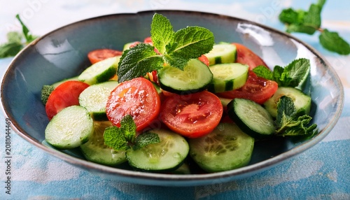 sliced cucumber and tomato salad garnished with fresh mint leaves fresh cucumber