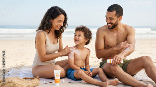 Family applying sunscreen together while sitting on the beach  