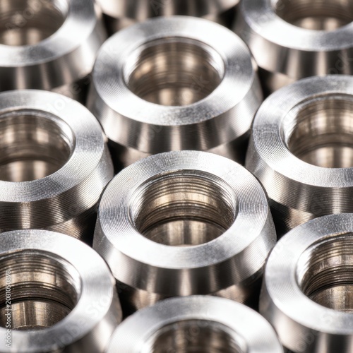 Precision-machined stainless steel spacers with threaded interiors arranged in a uniform pattern showcasing detailed metalwork and industrial craftsmanship in manufa