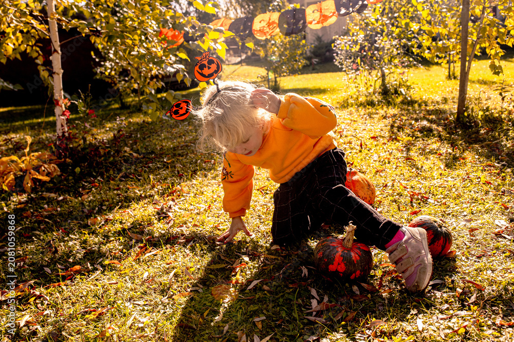 Fototapeta premium Child playing in a yard with pumpkins on Halloween