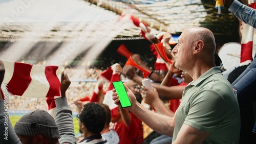Foto Vertical chroma key phone held by passionate supporter during live soccer match in a packed football stadium, Crowd cheering, fan chants and emotional sports reactions, match day with joy