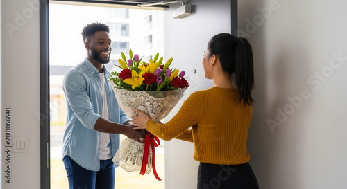 Man delivers bouquet of flowers to woman at doorway