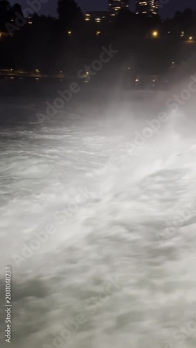 SCHAFFHAUSEN, SWITZERLAND - OCTOBER 11, 2025: Night view of the illuminated Rhine Falls with powerful cascading water and city lights surrounding the famous natural landmark.