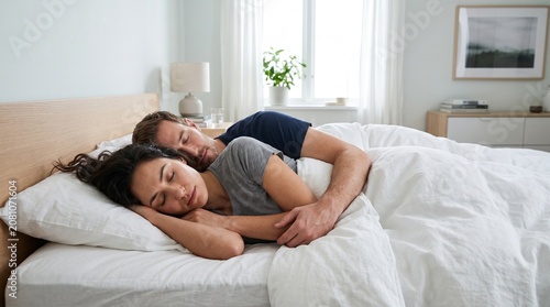 Couple Sleeping Peacefully in Bed Embracing Each Other Under White Duvet in Bright Bedroom