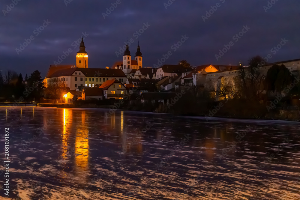 Obraz premium Telc town buildings reflecting on frozen pond at dusk