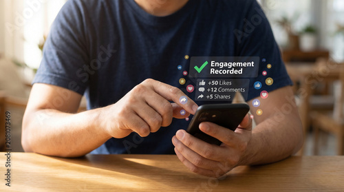 A person in a navy blue t-shirt uses a sleek black smartphone to view digital social media engagement metrics including likes comments and share counts