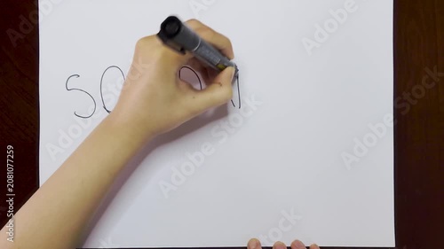 Hands Writing Solidarity on White Paper Over Brown Wooden Table Top View