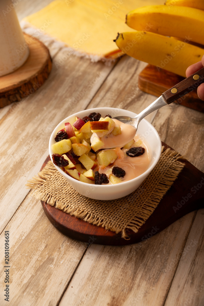 Fototapeta premium Yogurt with apple and dried cranberries, a light and healthy option to start breakfast.