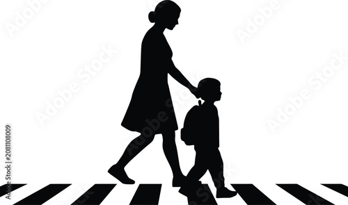 Silhouette of a mother walking with her young son to school on a pedestrian crossing