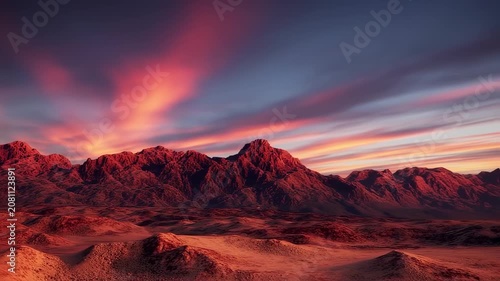 Dramatic sunset illuminates red mountain range & desert landscape with streaked pink and orange clouds