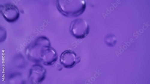 Floating, translucent bubbles suspended in a violet-toned liquid, creating a macro shot