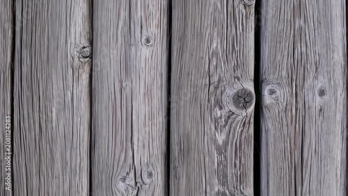 Close-up of weathered, vertical wooden planks, featuring knots, grain, and subtle variations in gray tones