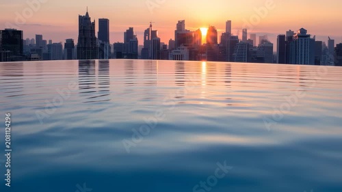 A cityscape silhouetted against a sunrise, reflected in a tranquil infinity pool