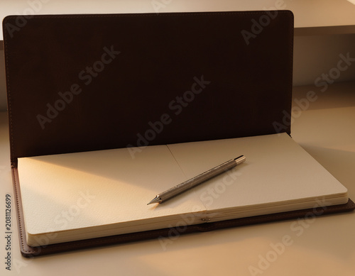 Open Leather Journal with Blank Pages and Metal Pencil Resting on a Wooden Desk Under Soft Sunlight