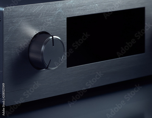 Close up of a professional brushed metal audio amplifier interface with a rotating volume control knob and blank digital screen display