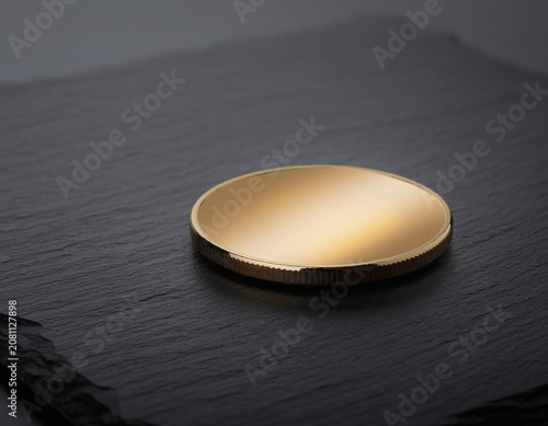 Blank Golden Metallic Coin Resting on a Textured Dark Stone Surface for Financial Concept