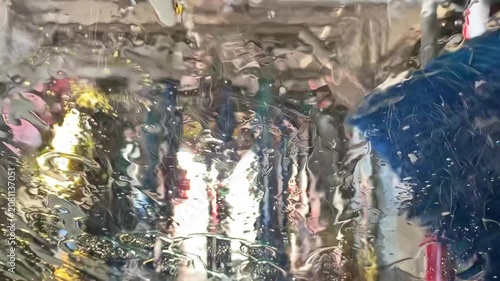 Conveyor car wash process, view from inside the vehicle: continuation of the foam wash and rinsing.
